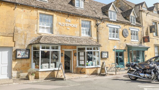 The Old Stocks Inn with stone facade, multiple windows, and a motorcycle parked outside. - The Apartment (Cheltenham)