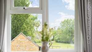 Ein Fenster mit Blick auf ein Ziegelgebäude und eine grüne Landschaft.