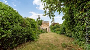 A narrow pathway leading to a brick house surrounded by dense greenery. - Holly Cottage (Warwick)