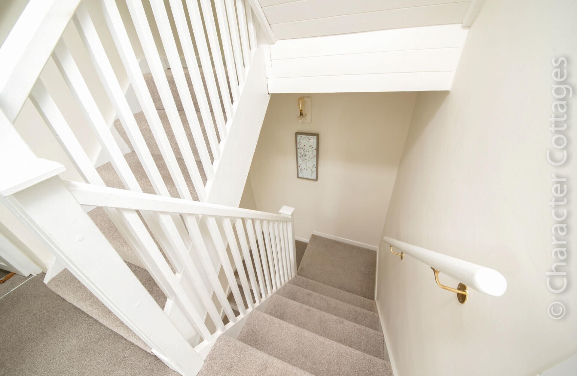 A staircase with white railings and beige carpet.