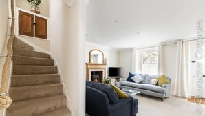 A living room with a fireplace, a sofa, a television, and a staircase. - Copperbeech (Cheltenham)
