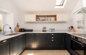 A modern kitchen with dark cabinetry, a built-in oven, and a window above the countertop.
