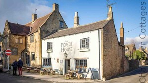The Porch House, a white building with a traditional stone facade, featuring a signboard and outdoor seating area. - Copperbeech (Cheltenham)