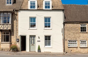 A two-story building with a white facade, multiple windows, and a small door with a sign above it. - Copperbeech (Cheltenham)