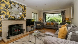 A living room with a fireplace, a television, and a sofa with cushions.