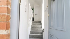 A narrow hallway with a carpeted staircase leading to a door with a heart-shaped decoration. - The Bath House (Moreton-in-Marsh)