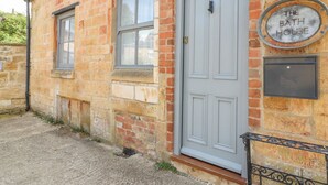 A building with a white door and a sign that reads "The Bath House." - The Bath House (Moreton-in-Marsh)