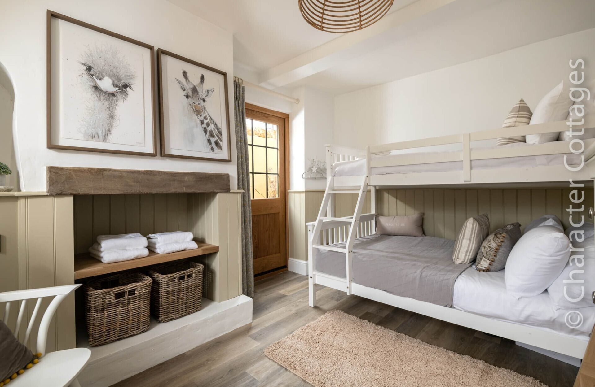 A bunk bed room with a wooden ladder, a shelf with folded towels, and wicker baskets.