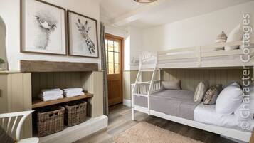 A bunk bed room with a wooden ladder, a shelf with folded towels, and wicker baskets.