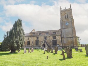 A historic church with a tall tower and a large tree in the foreground.