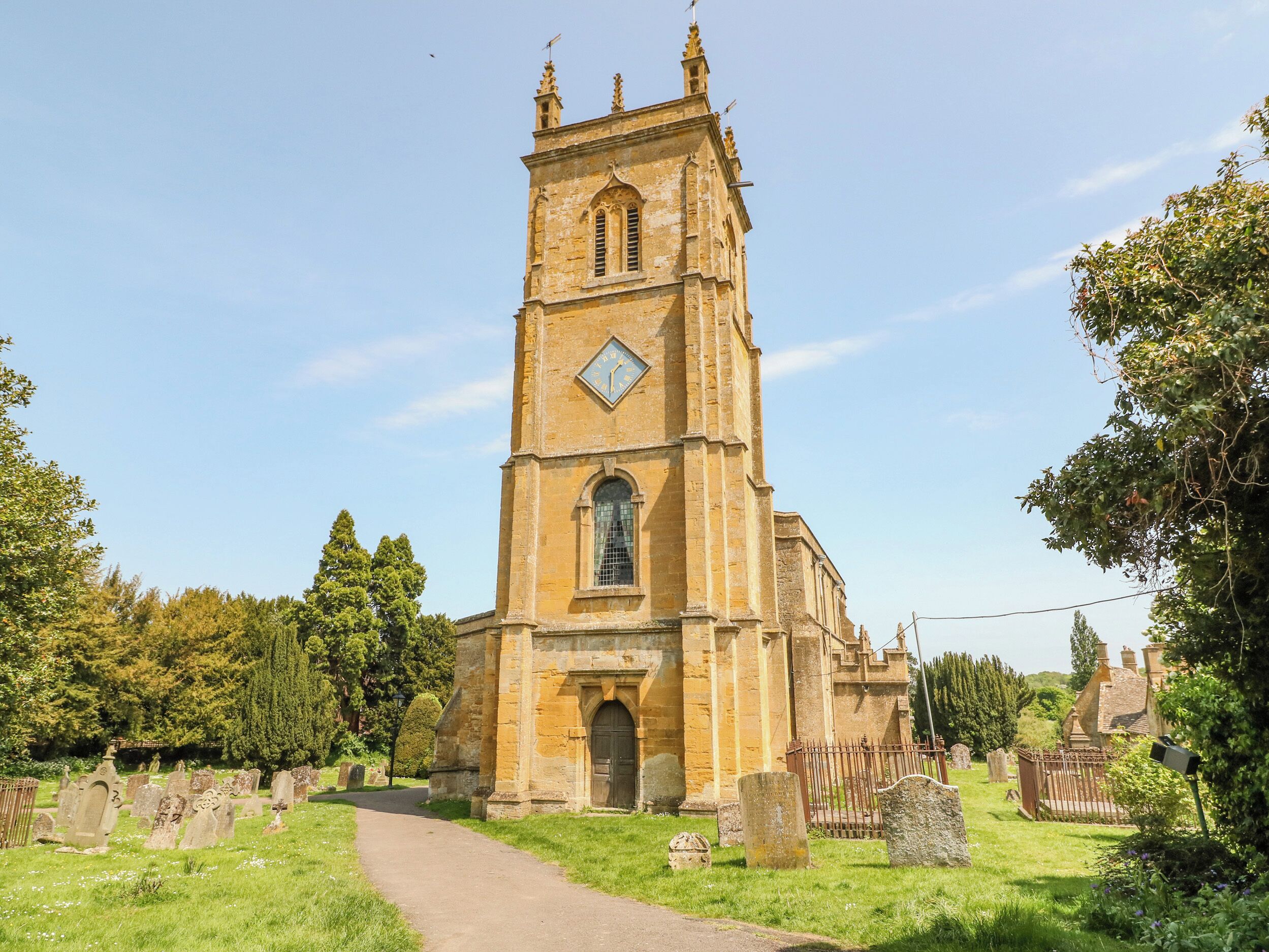A historic church with a tall tower, a central doorway, and a surrounding graveyard.