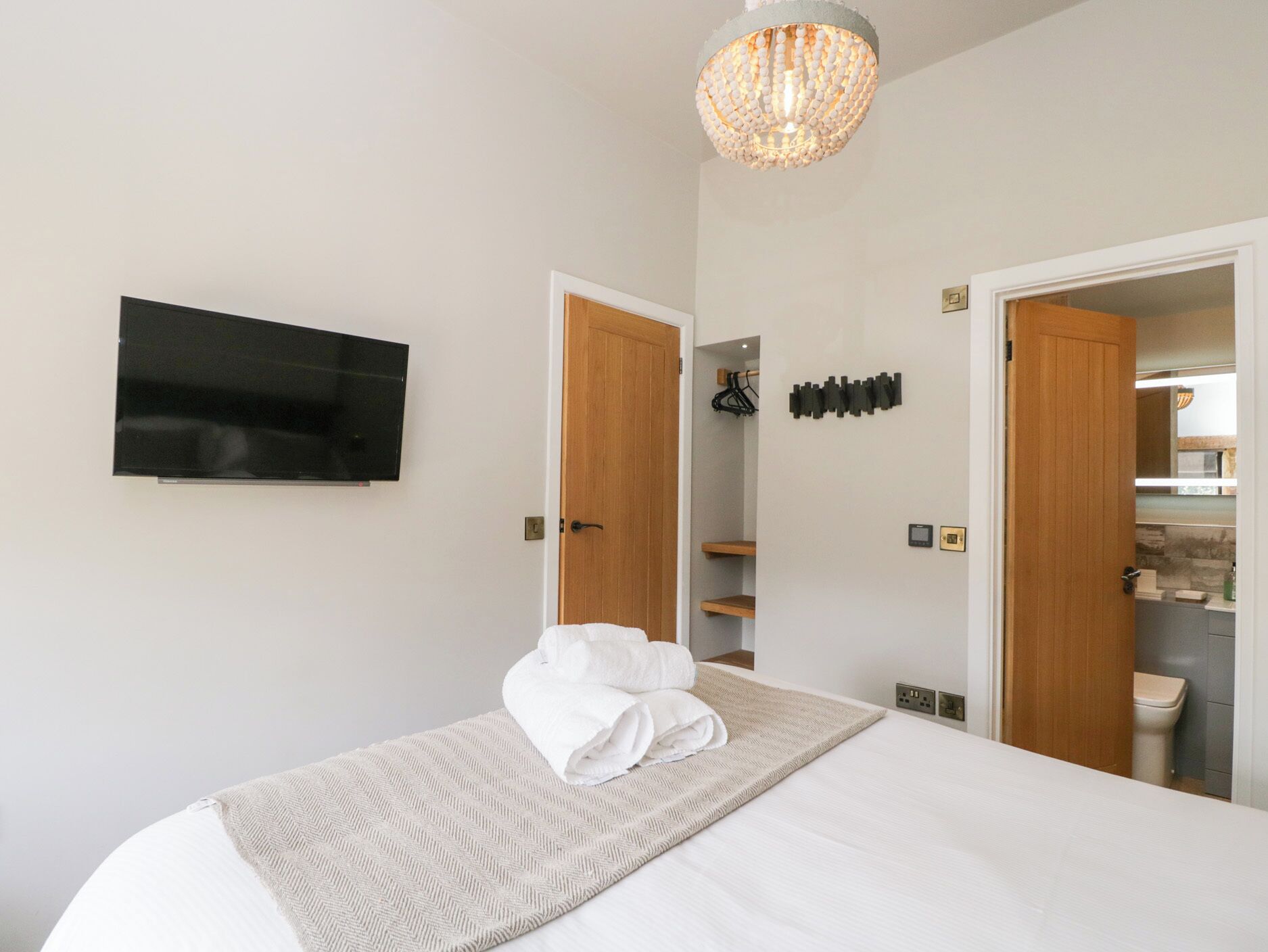 Ein Hotelzimmer mit Bett, Fernseher, einer Kandelaber und einem durchgehenden Tür sichtbaren Badezimmer.