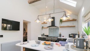 Una cocina moderna con una isla central, electrodomésticos integrados e iluminación colgante.
