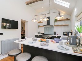 Una cocina moderna con una isla central, electrodomésticos integrados e iluminación colgante.