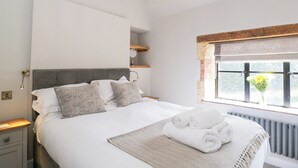 Un dormitorio moderno con una cama grande, una araña, una ventana con vistas y un radiador.