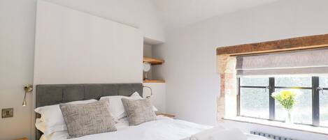 A modern bedroom with a large bed, a chandelier, a window with a view, and a radiator.