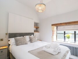 Un dormitorio moderno con una cama grande, una araña, una ventana con vistas y un radiador.