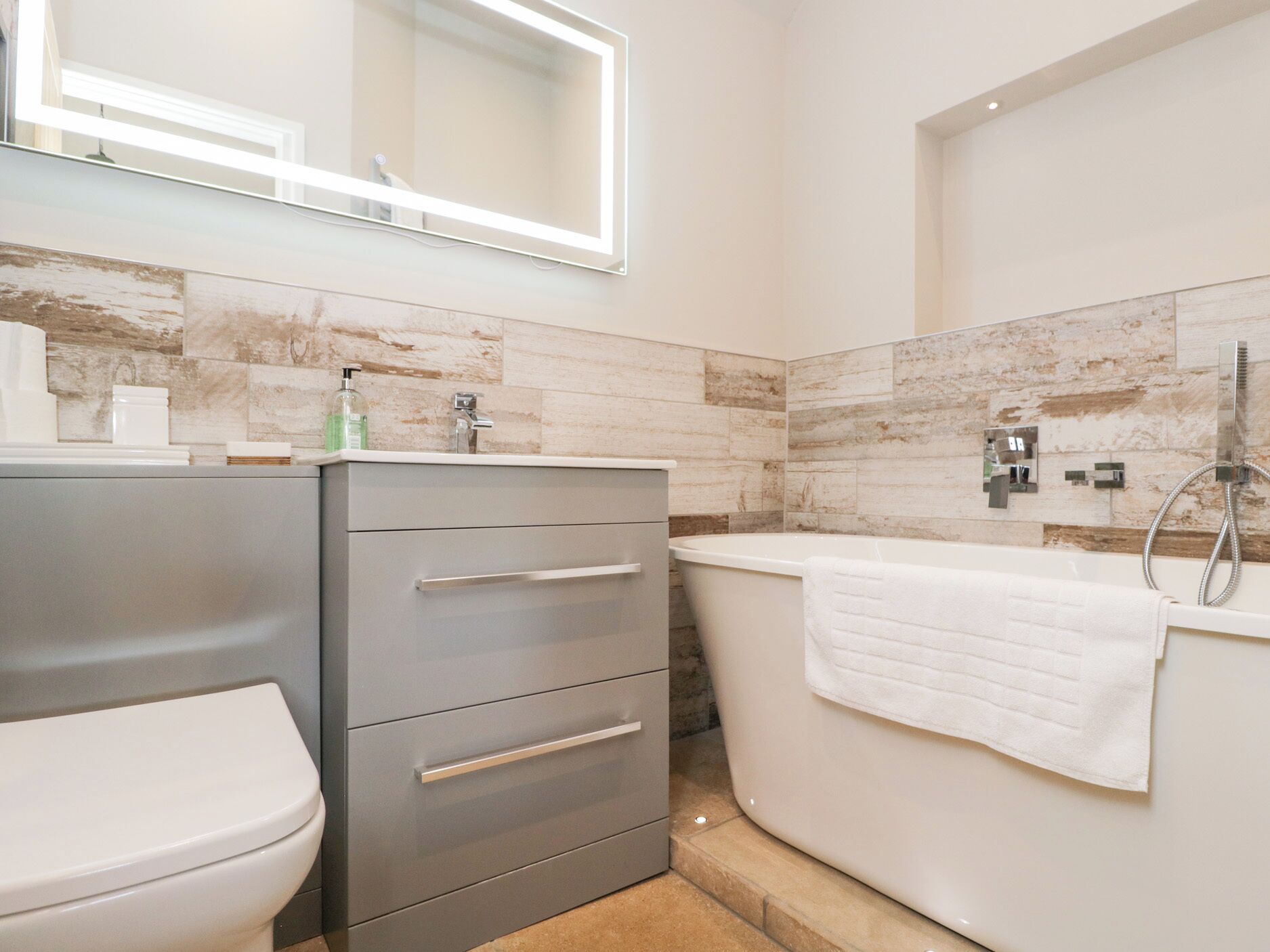 Een moderne badkamer met toilet, wastafel en bad.