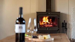 Une pièce chaleureuse avec un poêle à bois, une bouteille de vin et des verres posés sur une table en bois.