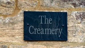 Ein Schild mit der Aufschrift 'The Creamery' an einer Steinmauer befestigt.