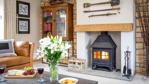 Un salon chaleureux avec une cheminée en pierre, un meuble en bois et une collection d’outils accrochés au mur.