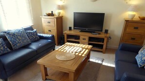 A living room with a sofa, a coffee table, a TV, and wooden cabinets.