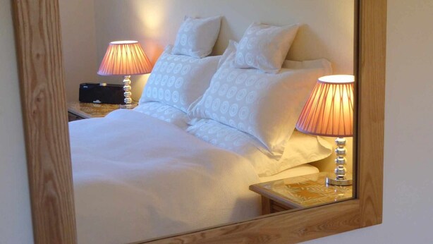 A neatly made bed with white bedding and two bedside lamps.