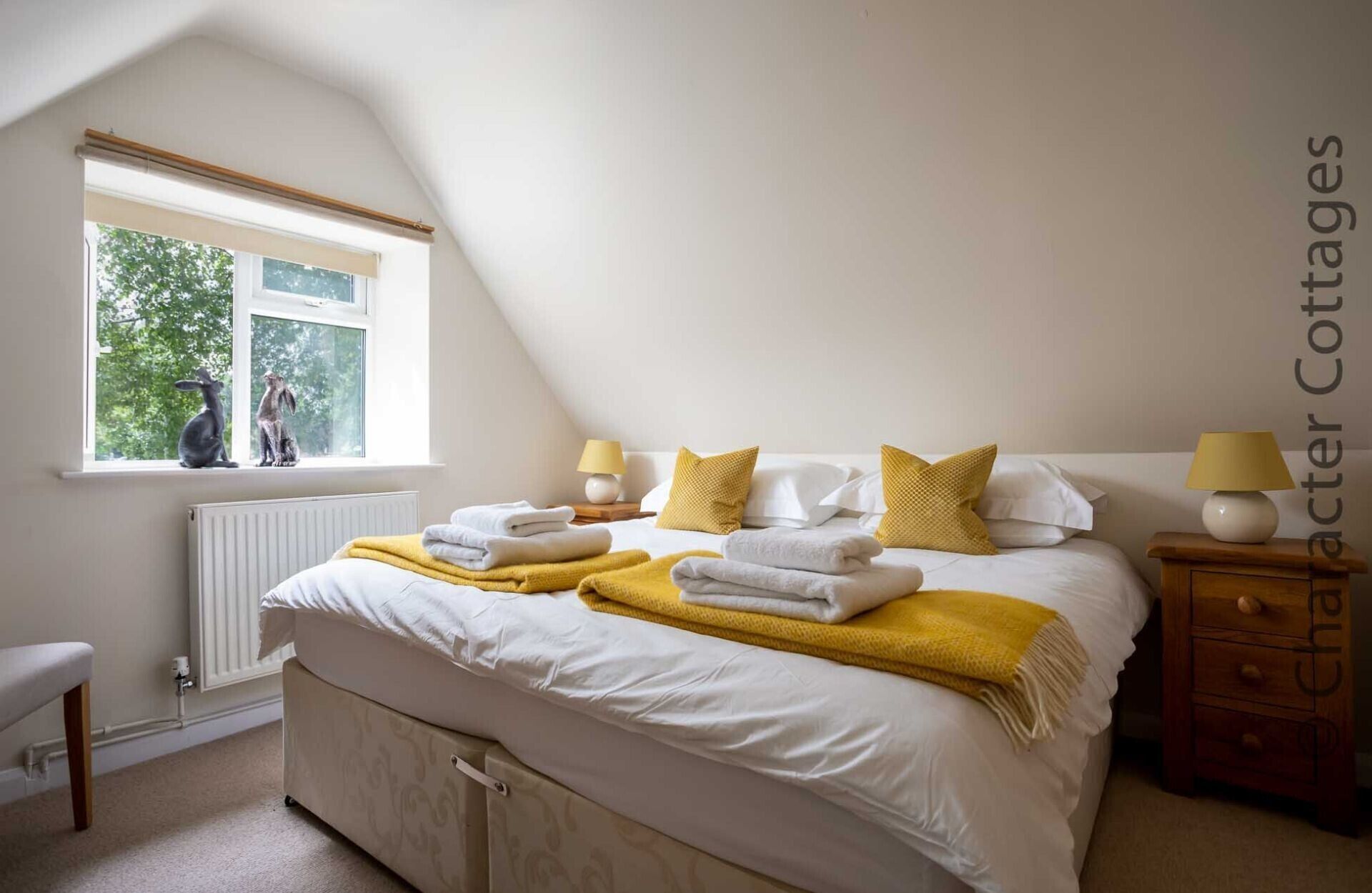 A bedroom with a bed, bedside tables, a window with a view, and a radiator.