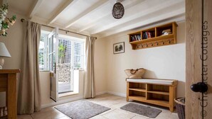 Une pièce chaleureuse avec un banc en bois, une bibliothèque et une porte donnant sur l’extérieur.