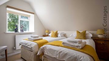 A bedroom with two beds, a window with a view of trees, and a radiator.