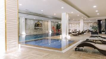 Un hall de hotel con piscina, sillones de descanso y un cartel que dice "ROYAL BEAUTY & SPA".