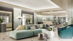 A modern hotel lobby with a sectional sofa, a teal armchair, and a round coffee table. - Somerset City Centre Atyrau (Atyrau)