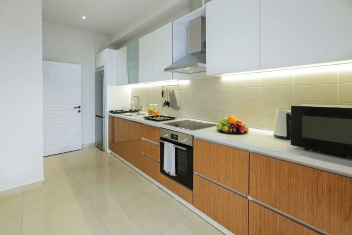 Una cocina moderna con armarios blancos, una estufa de acero inoxidable y un microondas.