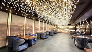 A modern restaurant with a long dining area, high ceilings, and a decorative light installation. - Somerset City Centre Atyrau (Atyrau)