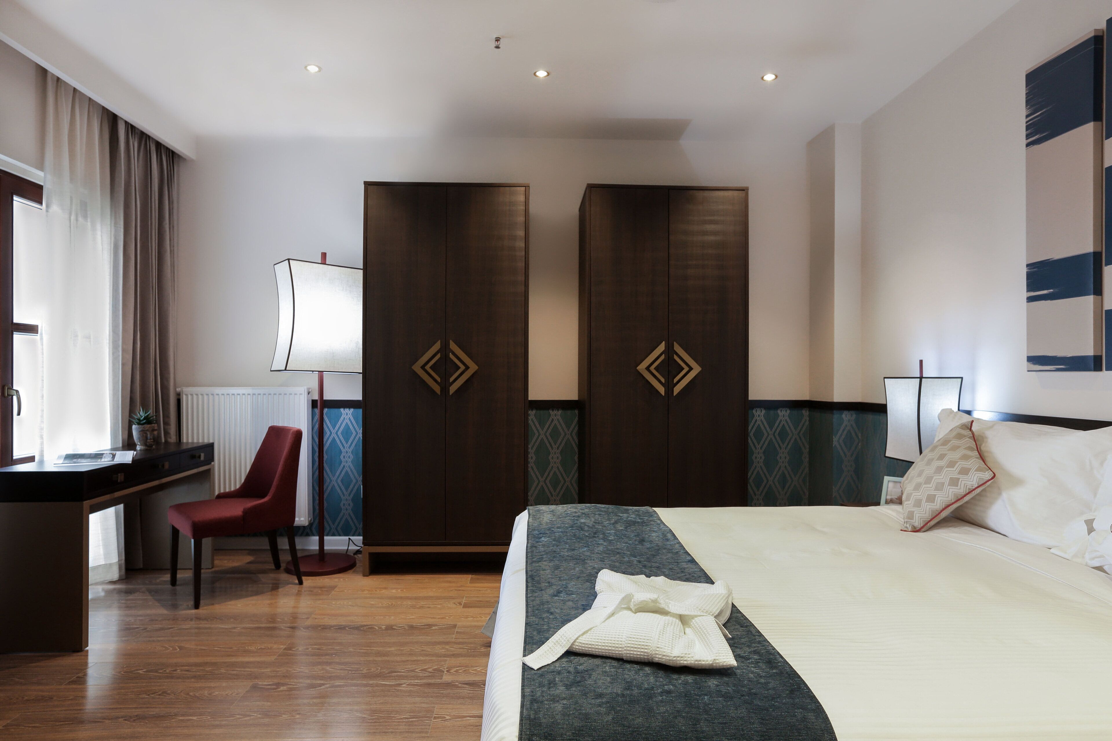 A hotel room with a bed, a desk, a chair, and a wardrobe.