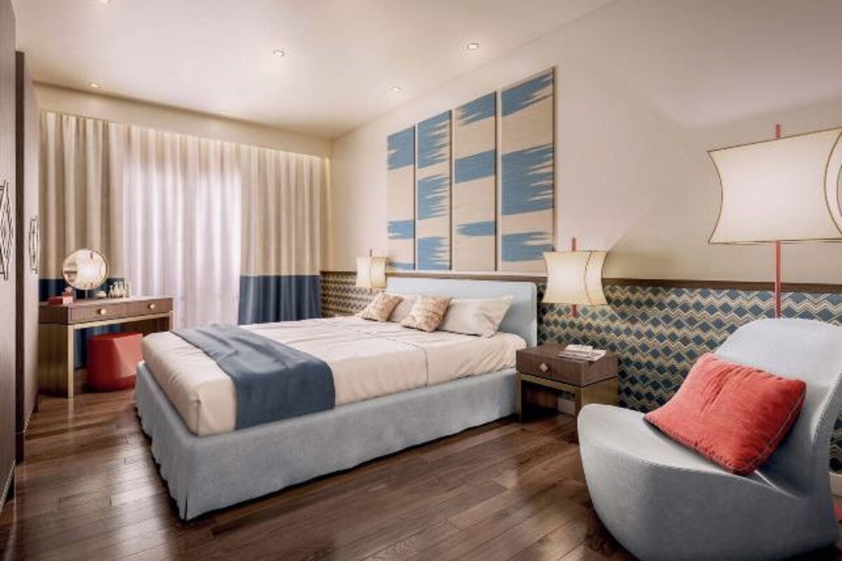 Habitación de hotel moderna con una cama grande, un escritorio, una silla y una pared decorada con arte abstracto.