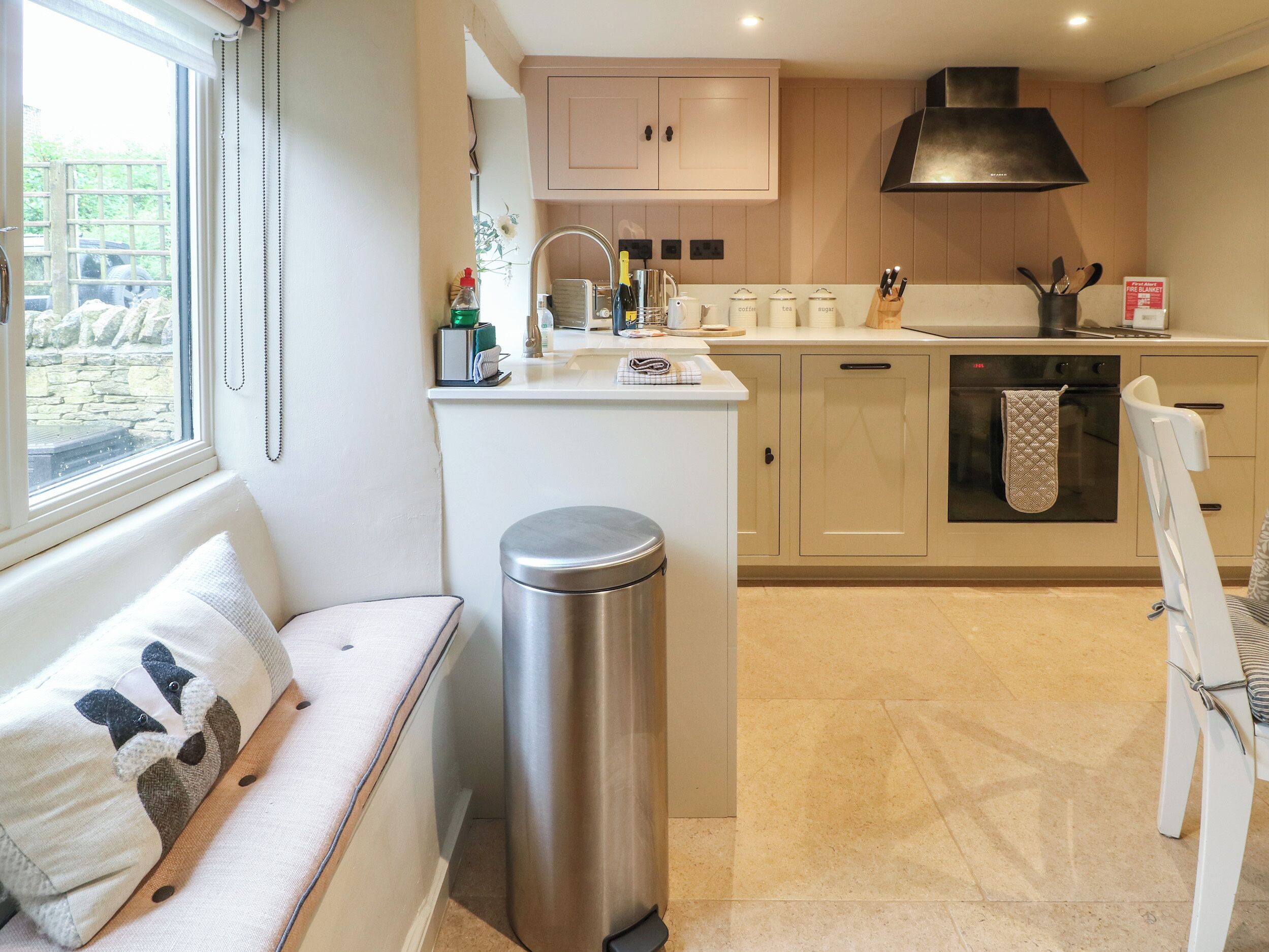 Una cocina compacta con horno integrado, lavamanos y ventana con cortinas.