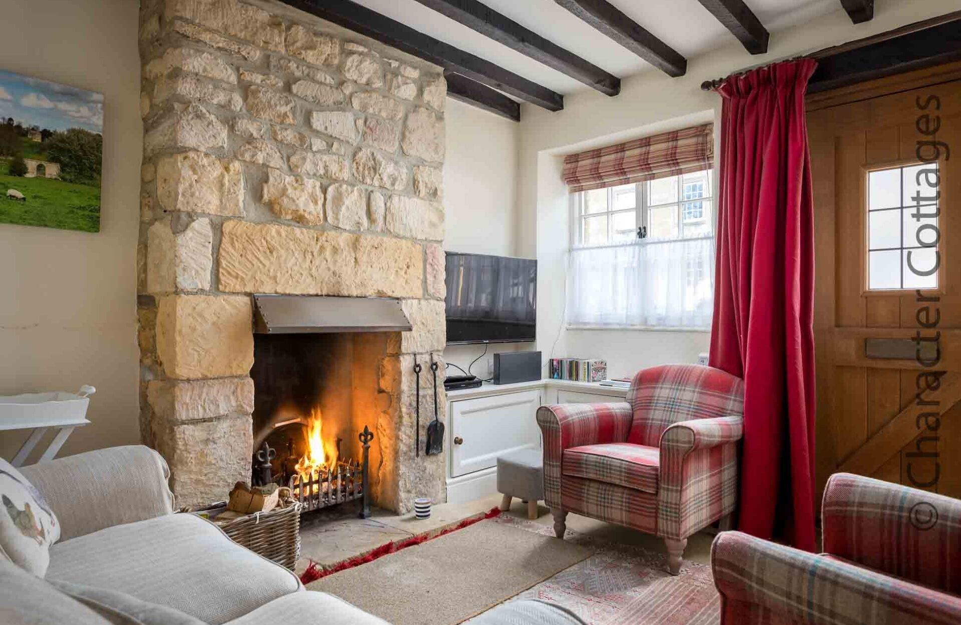 A cozy room with a stone fireplace, plaid furniture, and a television.