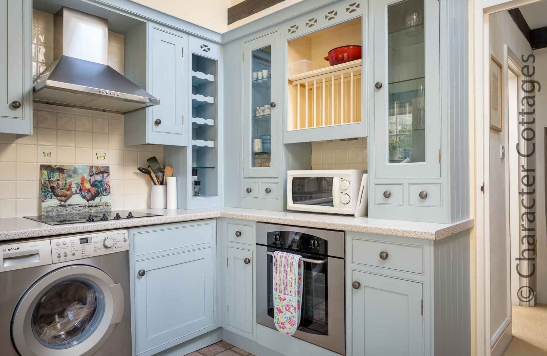 A compact kitchen with a Bosch washing machine, a microwave, and a stove.