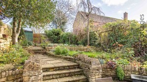 A stone staircase leading up to a house surrounded by lush greenery and a garden. - Lanes Cottage (Chipping Campden)