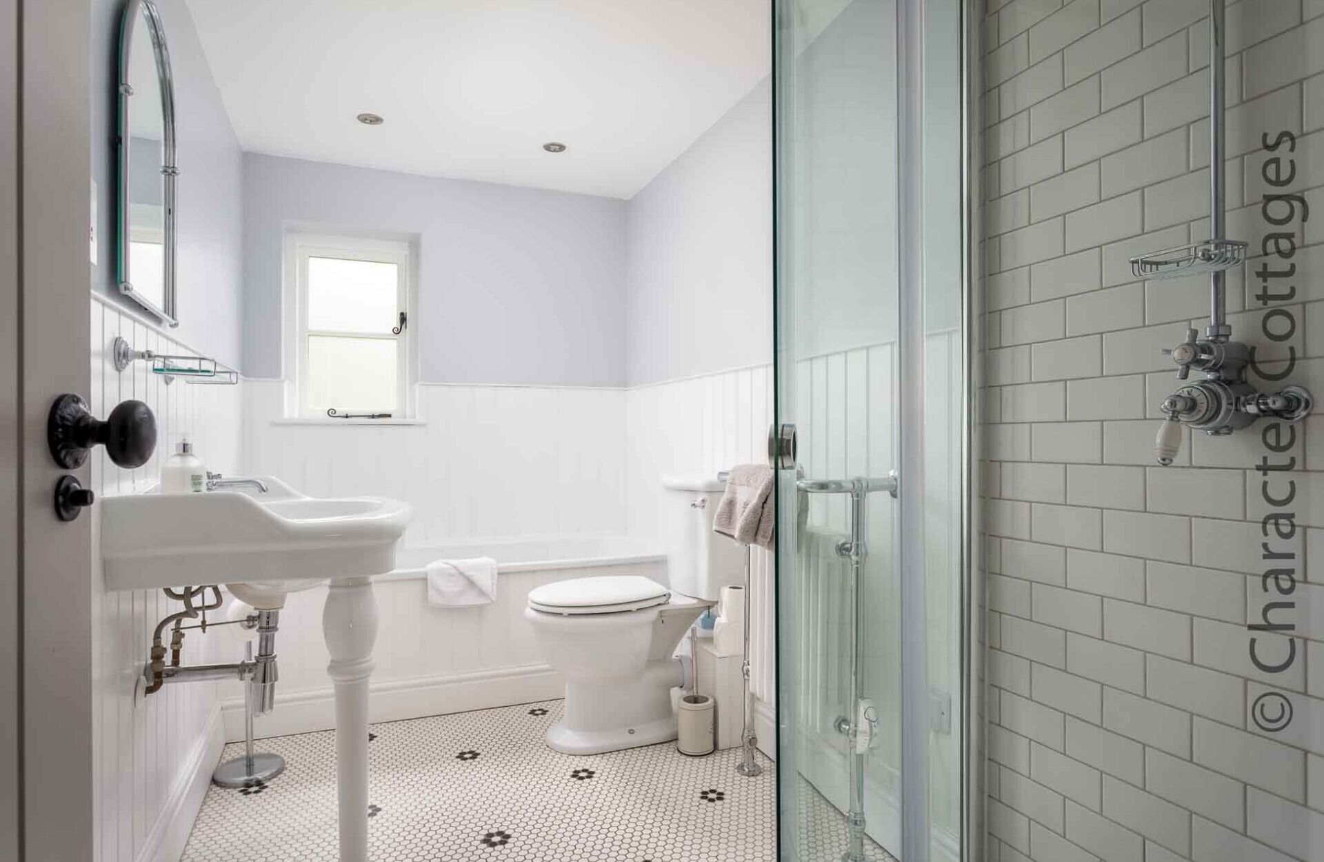A modern bathroom with a white sink, toilet, and shower area.