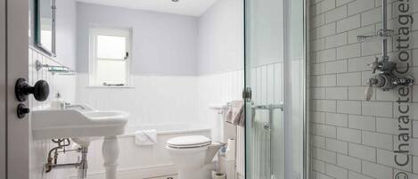 A modern bathroom with a white sink, toilet, and shower area.