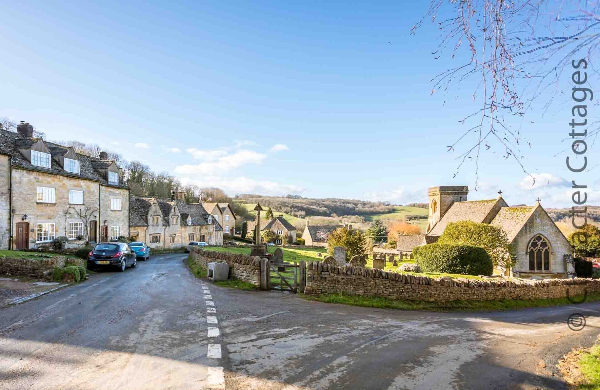 A rural road with stone cottages, a church, and a stone wall.