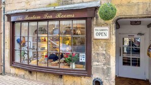 The Bantam Tea Rooms met een grote etalage, een bord waarop staat dat de theetuin geopend is, en een deur met een duwbeugel.