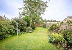 Un jardín cuidado con diversos tipos de plantas y un camino despejado que lleva a una casa.