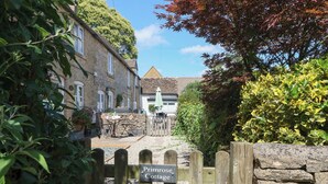 A stone cottage with a sign reading "Primrose Cottage" at the entrance. - Primrose Cottage (Cheltenham)
