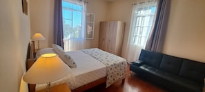 Ein Schlafzimmer mit einem Bett, einer Nachttischlampe, einem Kleiderschrank und einem schwarzen Sofa.