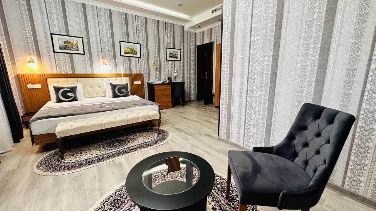 A bedroom with a bed, bedside tables, a chair, and a round coffee table.
