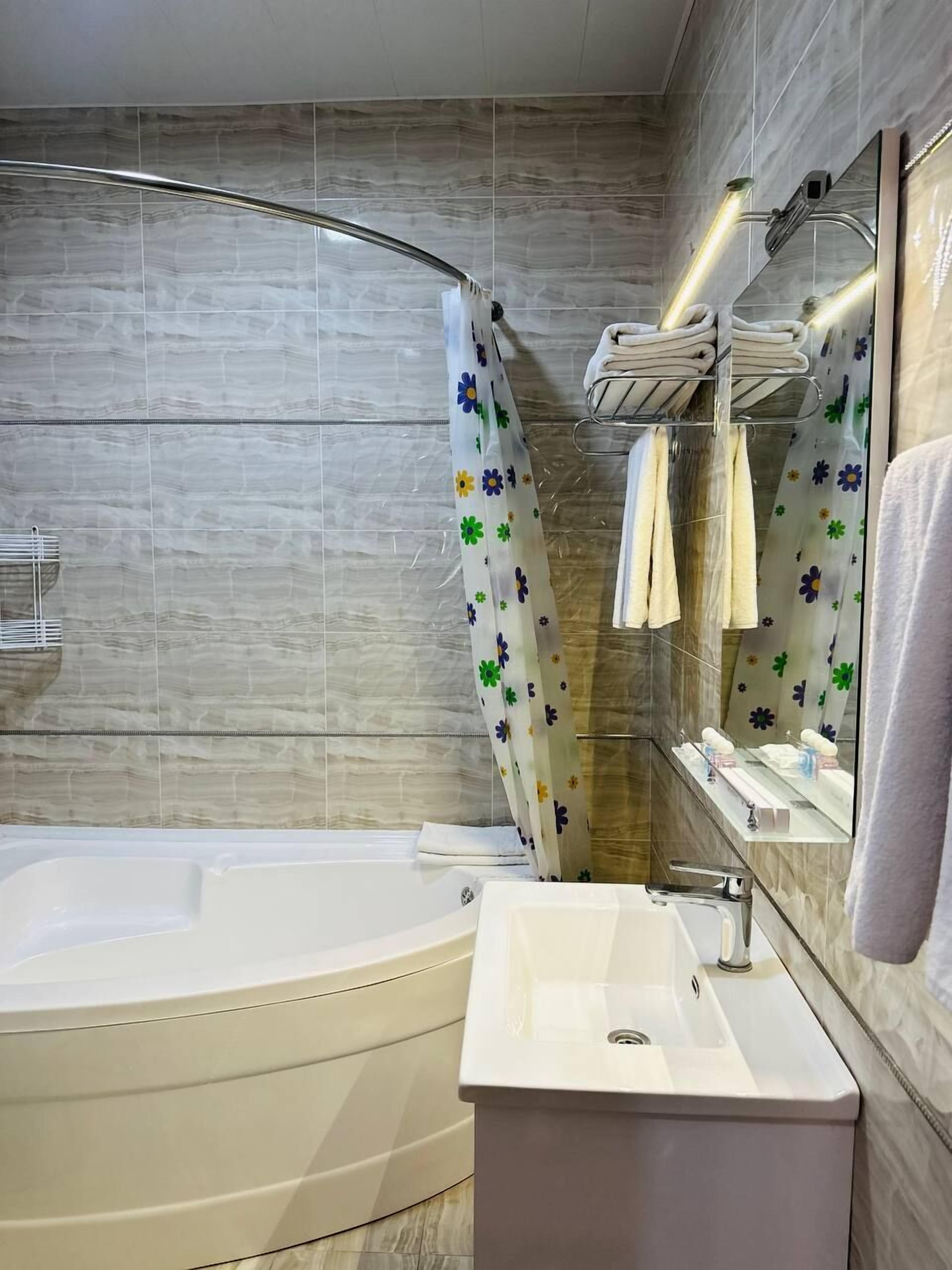 Un baño moderno con una bañera independiente, un tocador con lavamanos y un espejo sobre el lavamanos.