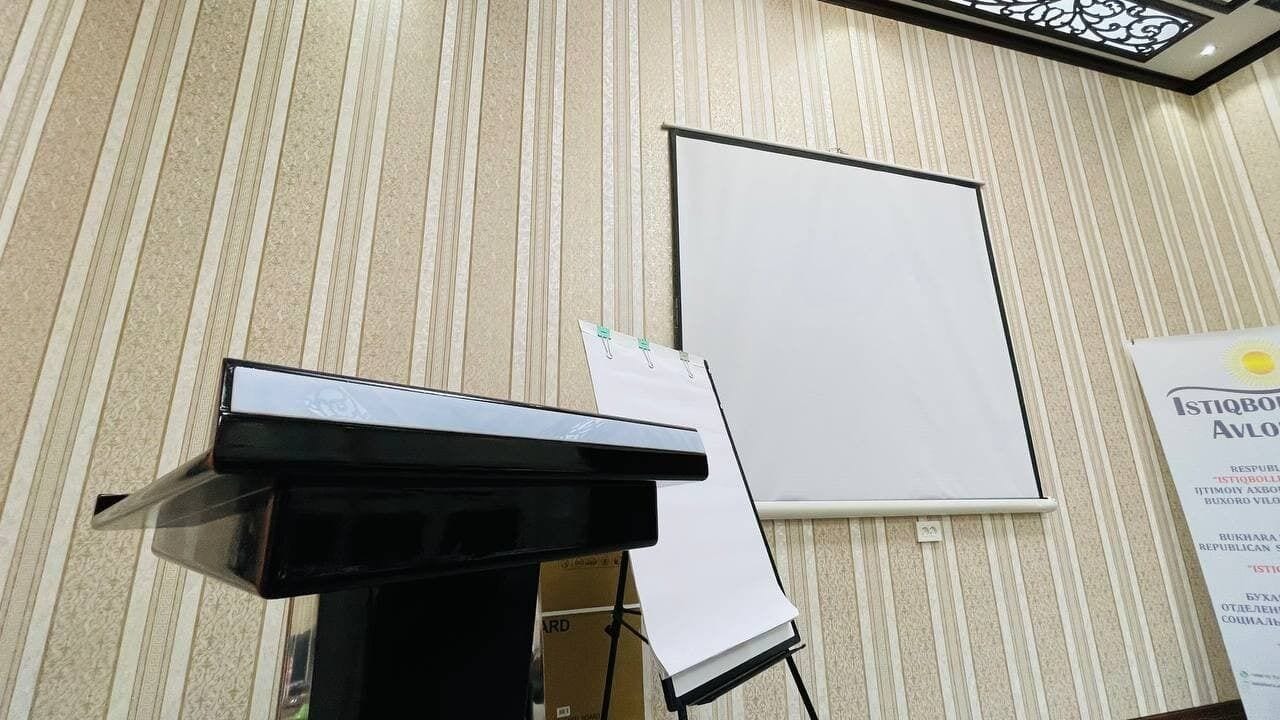 A conference room with a podium, a whiteboard, and a sign on the wall.